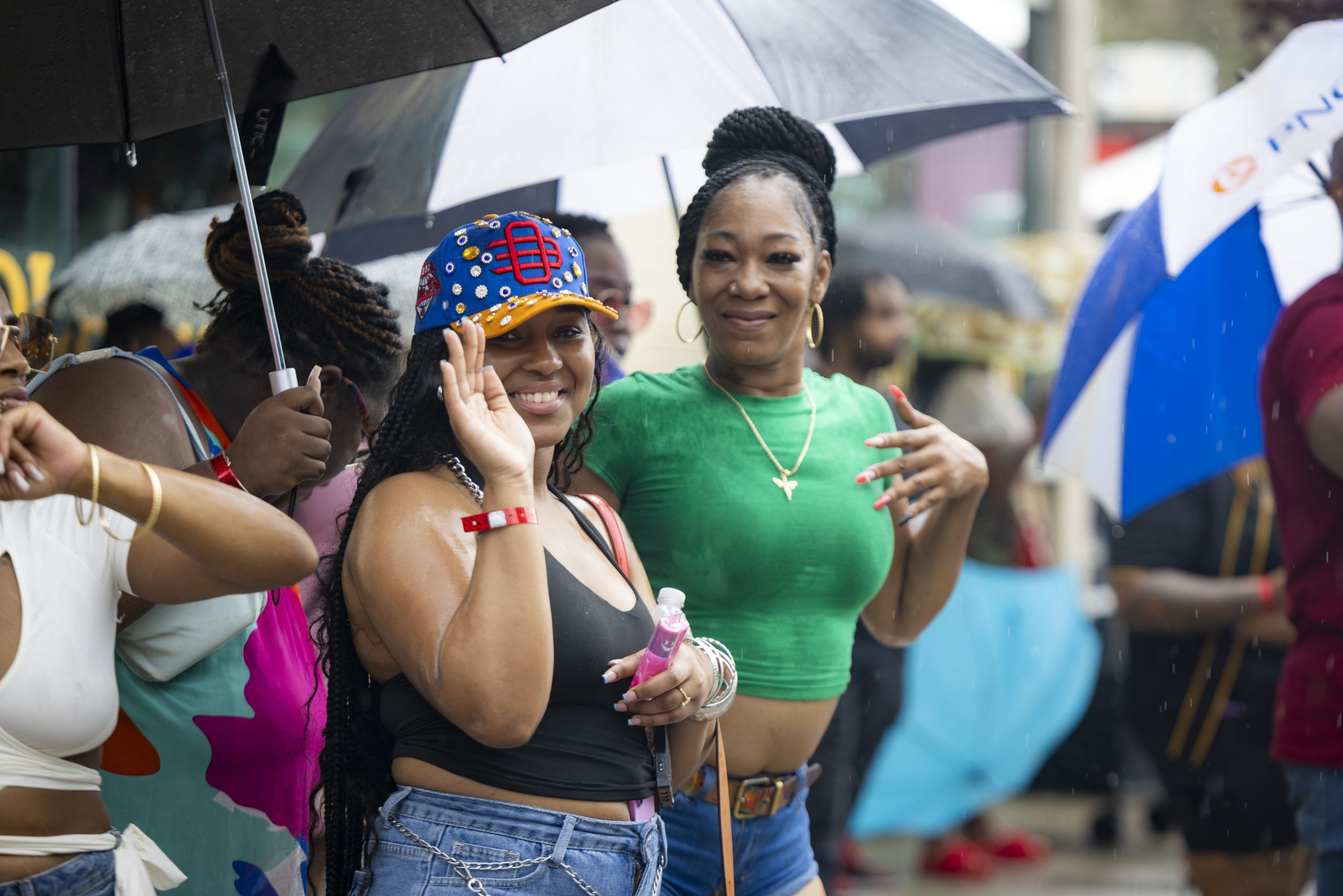 Two attendees smiling under umbrellas in the rain at an outdoor Slappers N Bangers party in Pittsburgh