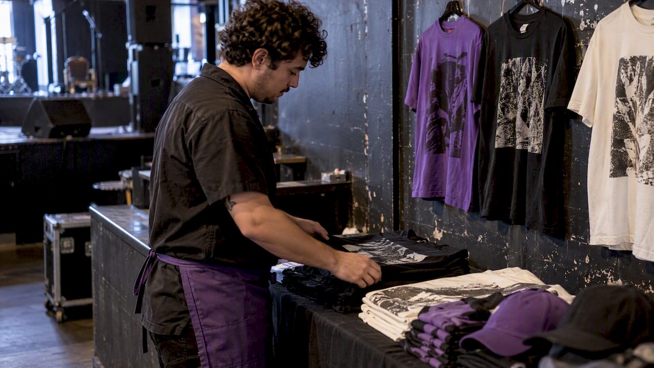 Staffer arranging tees and hats at a venue