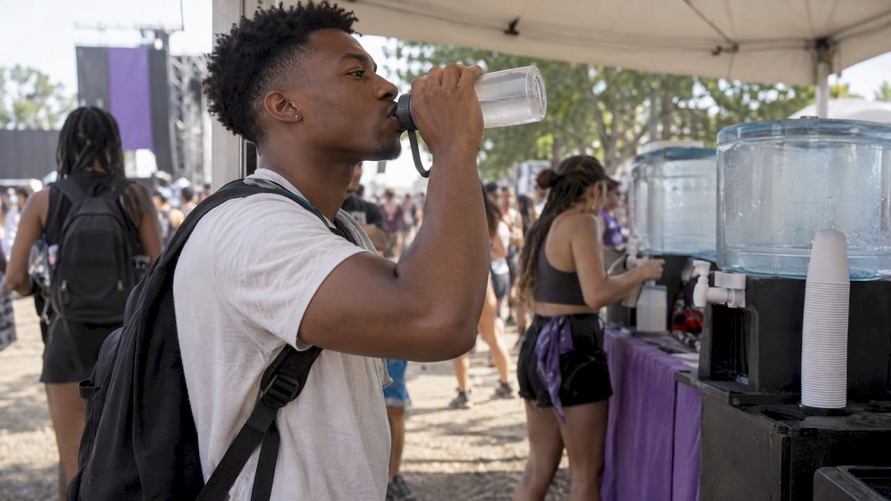 Festival attendee drinking water in shaded area